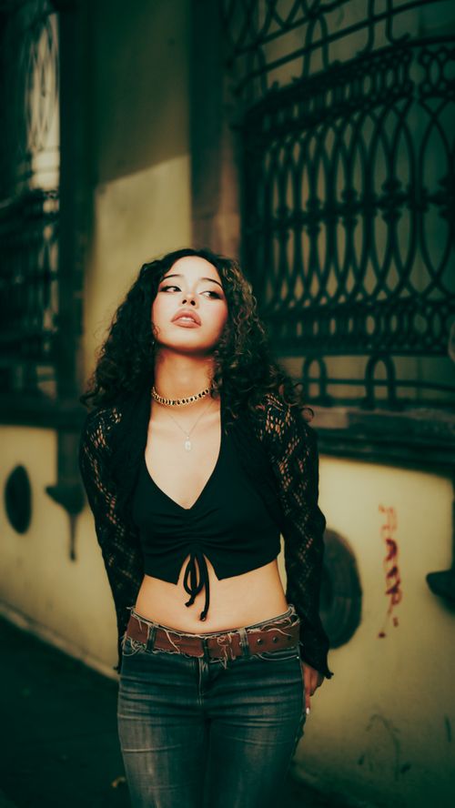 Free Stylish young woman in black top poses against an old architectural background outdoors. Stock Photo