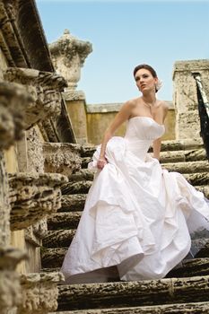 Stunning bride in a white dress poses on a historical stone staircase in Miami, Florida.