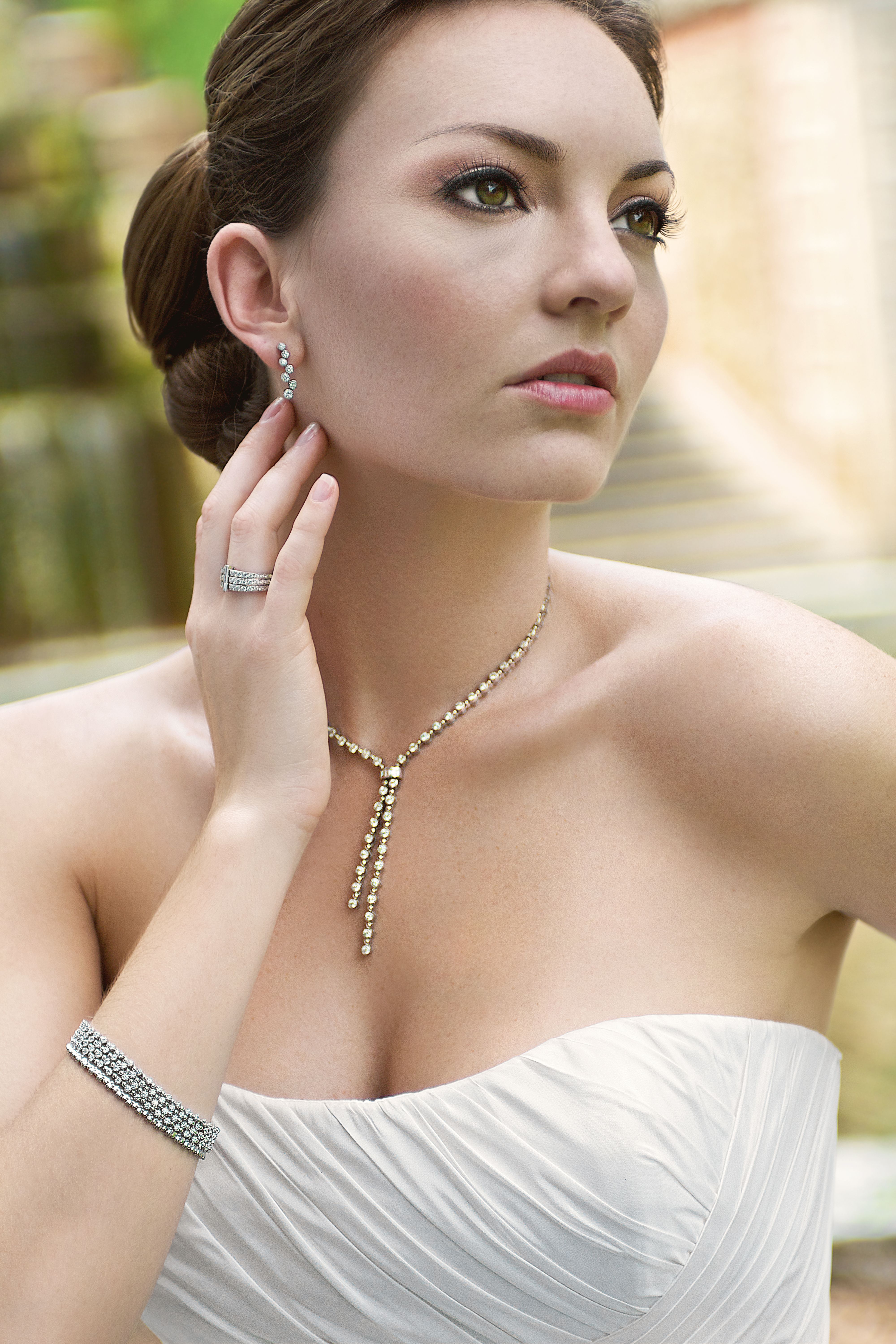 Sophisticated bridal portrait with elegant jewelry in an outdoor setting.