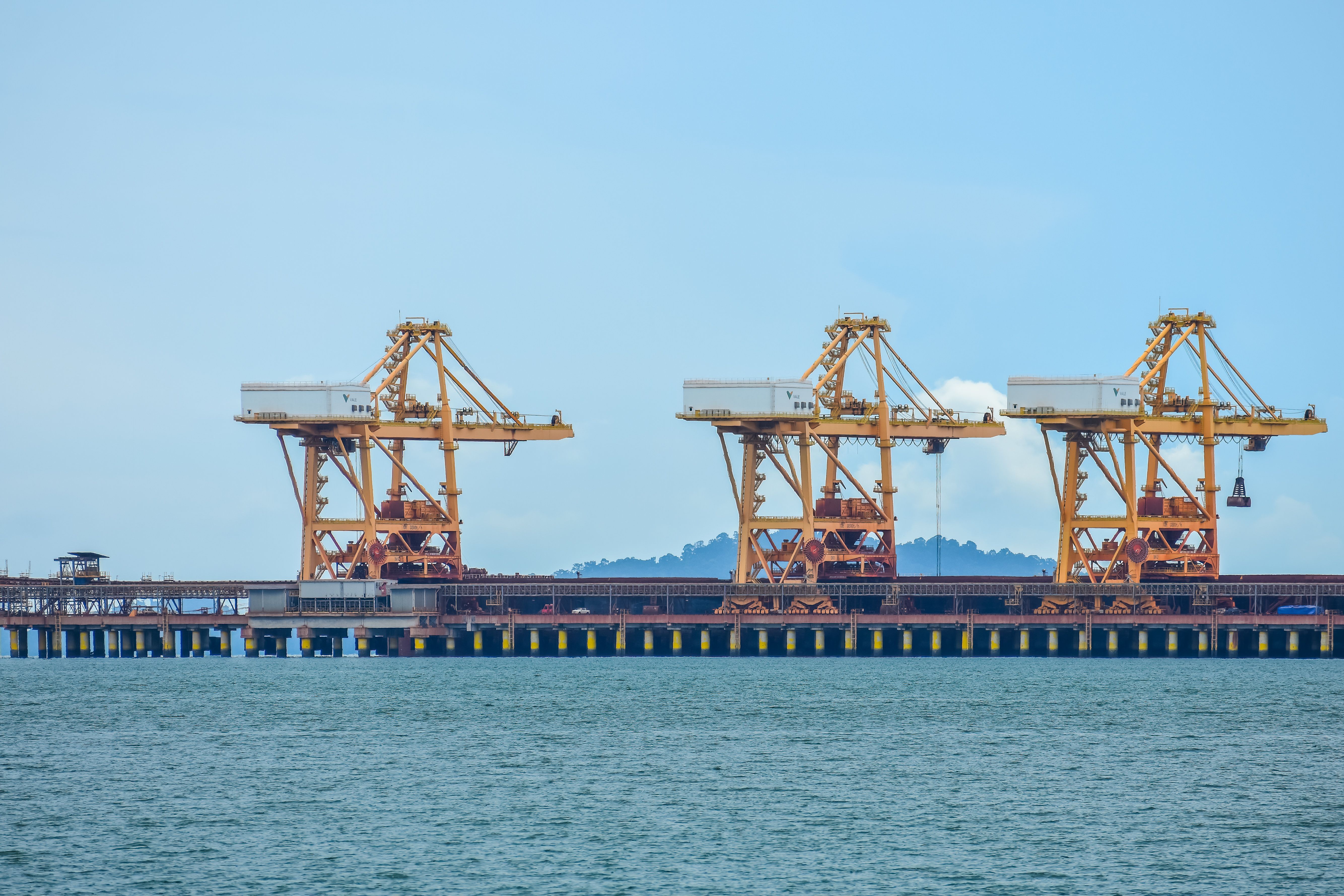 Temsilî fotoğraf: Yellow industrial port cranes stand over water in Lumut, Malaysia, against a clear blue sky.