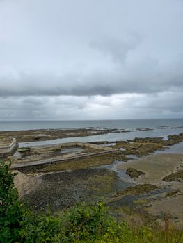 Moody coastal view of St Andrews beach with rocky shoreline and cloudy skies.