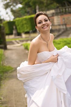 Elegant bride in white gown smiling joyfully outdoors at Vizcaya Museum Gardens in Miami.