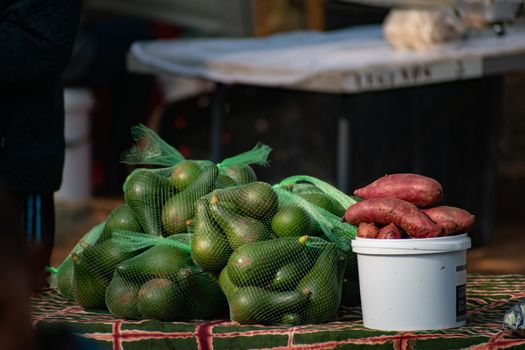 Bags of avocados and sweet potatoes at an outdoor market in Manzini, Eswatini.
