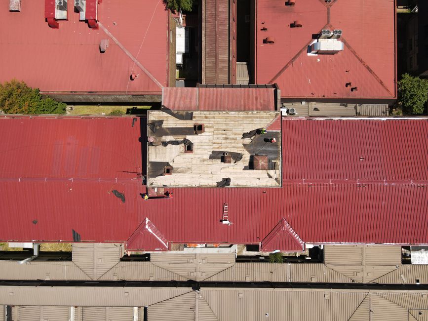 Drone shot of red-roofed cityscape with workers visible during summer day.