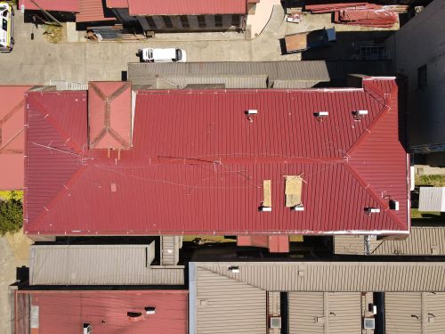 Free Aerial view showcasing vibrant red metal rooftops in a city, highlighting architectural patterns and urban organization. Stock Photo