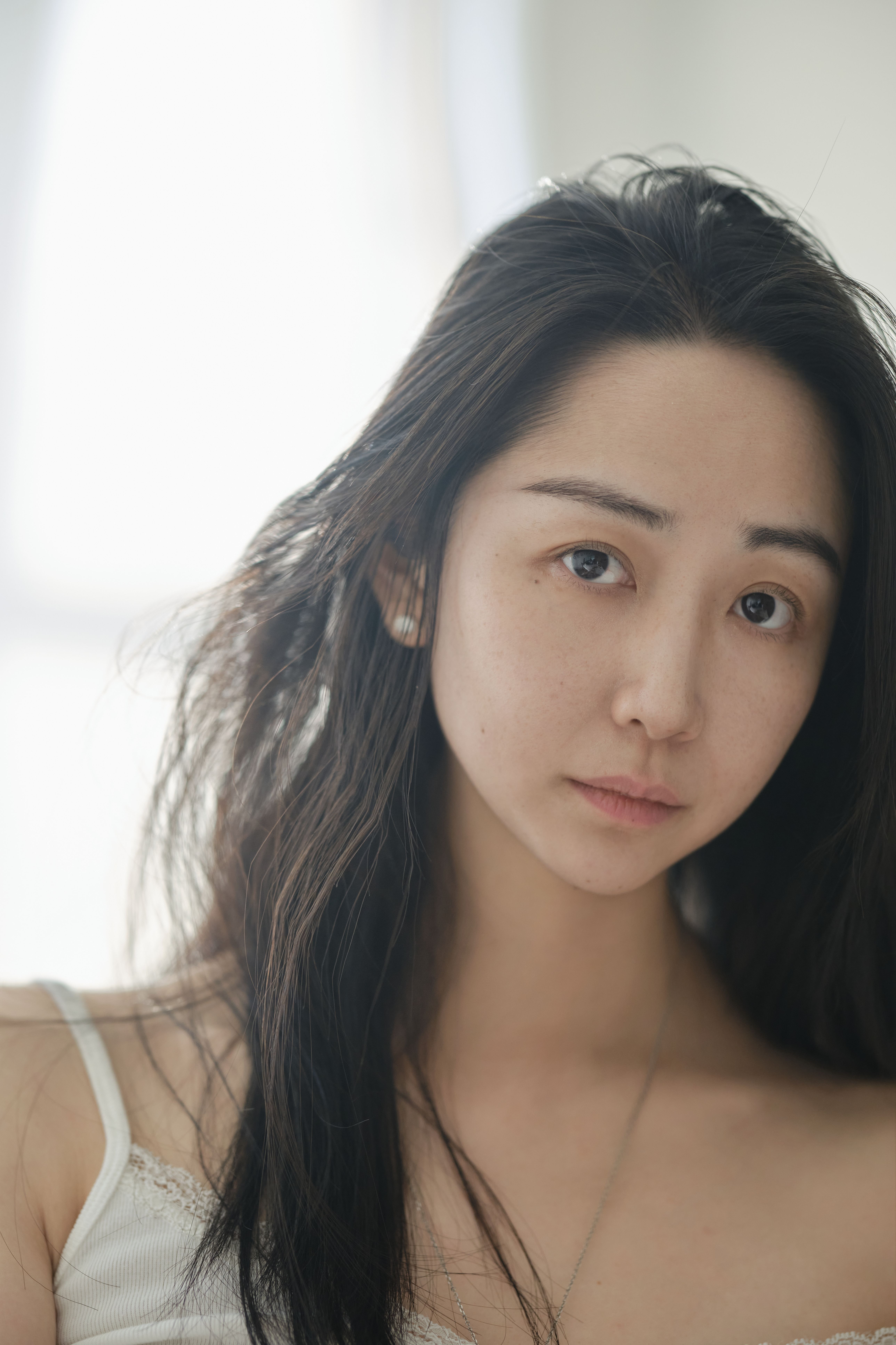 Close-up portrait of a young woman with long hair and a neutral expression.