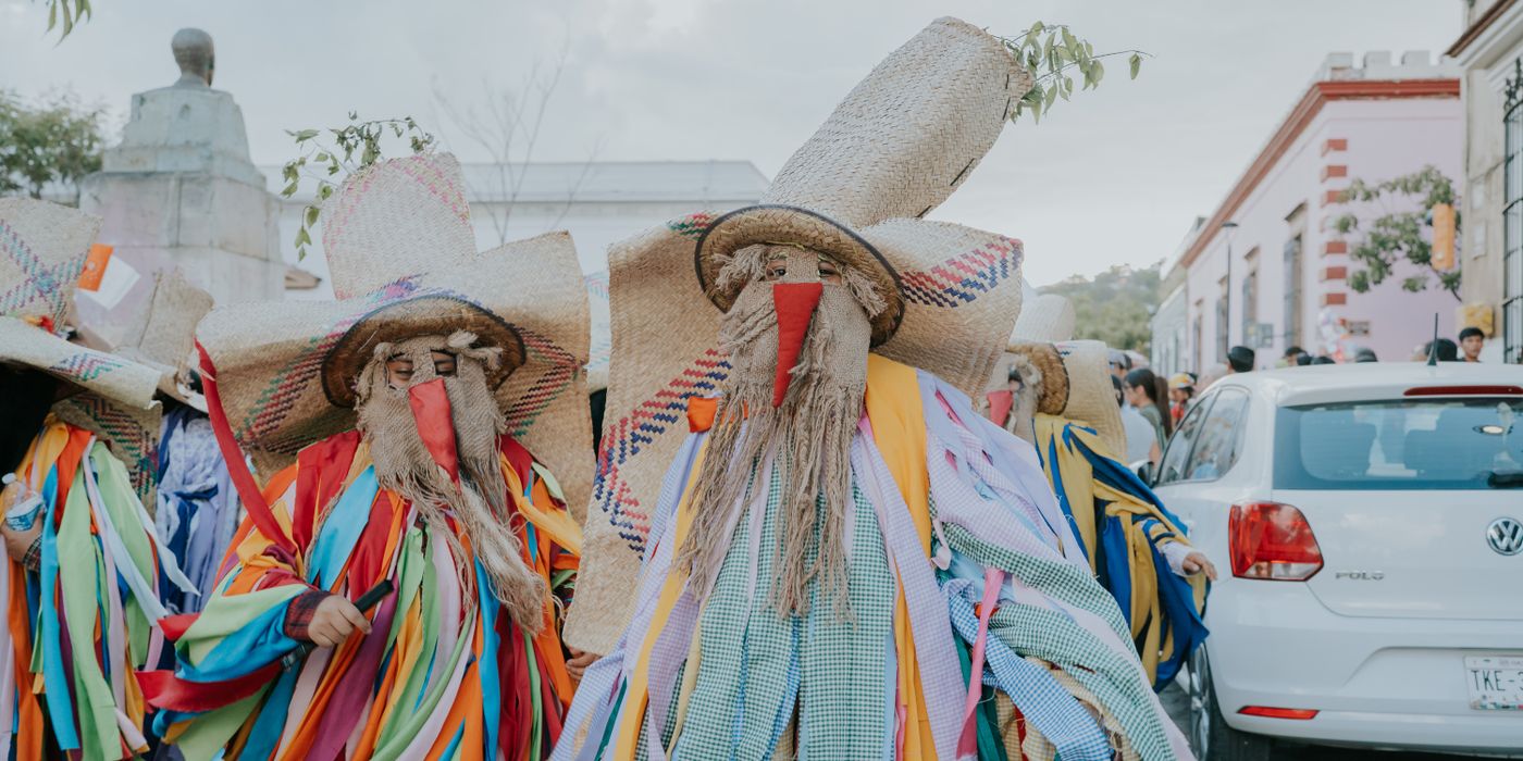 A street parade in Oaxaca with participants in traditional costumes and colorful decorations