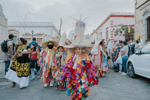 A vibrant street parade in Oaxaca featuring traditional Mexican costumes and locals celebrating.