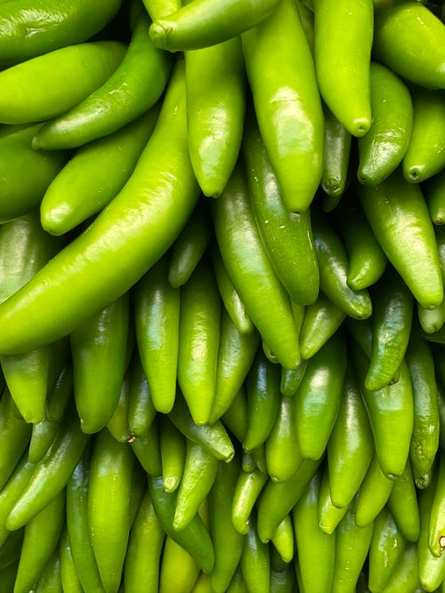 Free Vibrant close-up of fresh green serrano peppers piled together, showcasing their texture and color. Stock Photo