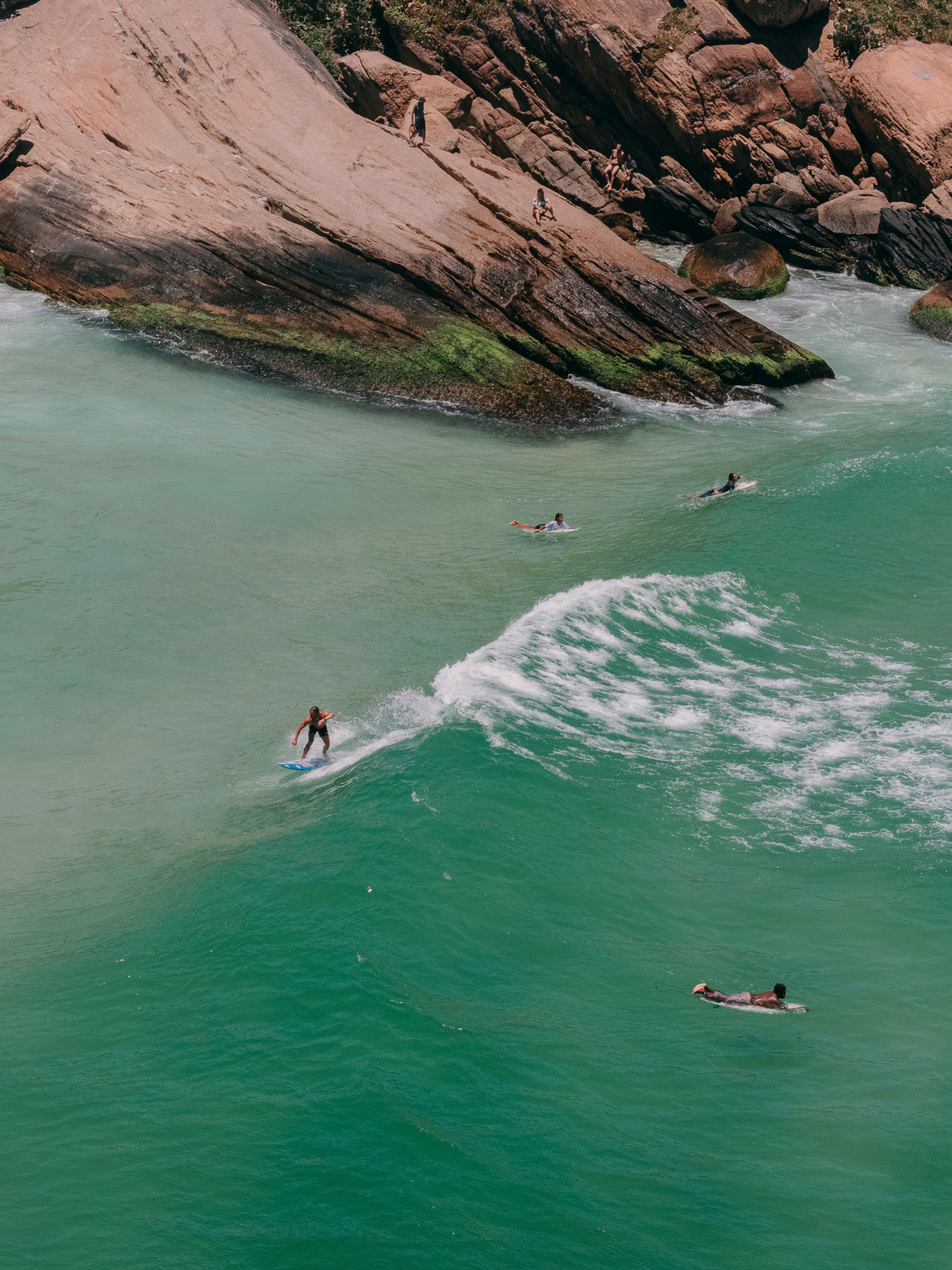 An aerial shot of surfers riding waves at Prainha Beach, Rio de Janeiro, showcasing vibrant ocean scenery.