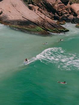 An aerial shot of surfers riding waves at Prainha Beach, Rio de Janeiro, showcasing vibrant ocean scenery.