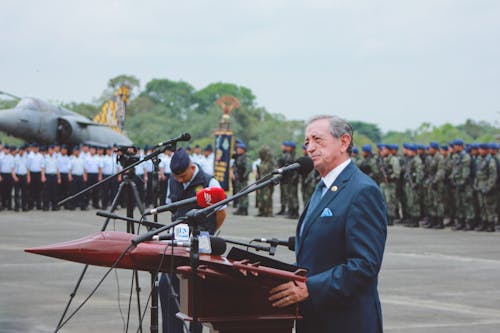 General Sério De Terno Discursando Atrás Do Exército Durante A Celebração