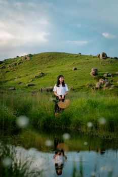 A woman stands by a reflective pond in a lush meadow, ML, India, enjoying a peaceful day.