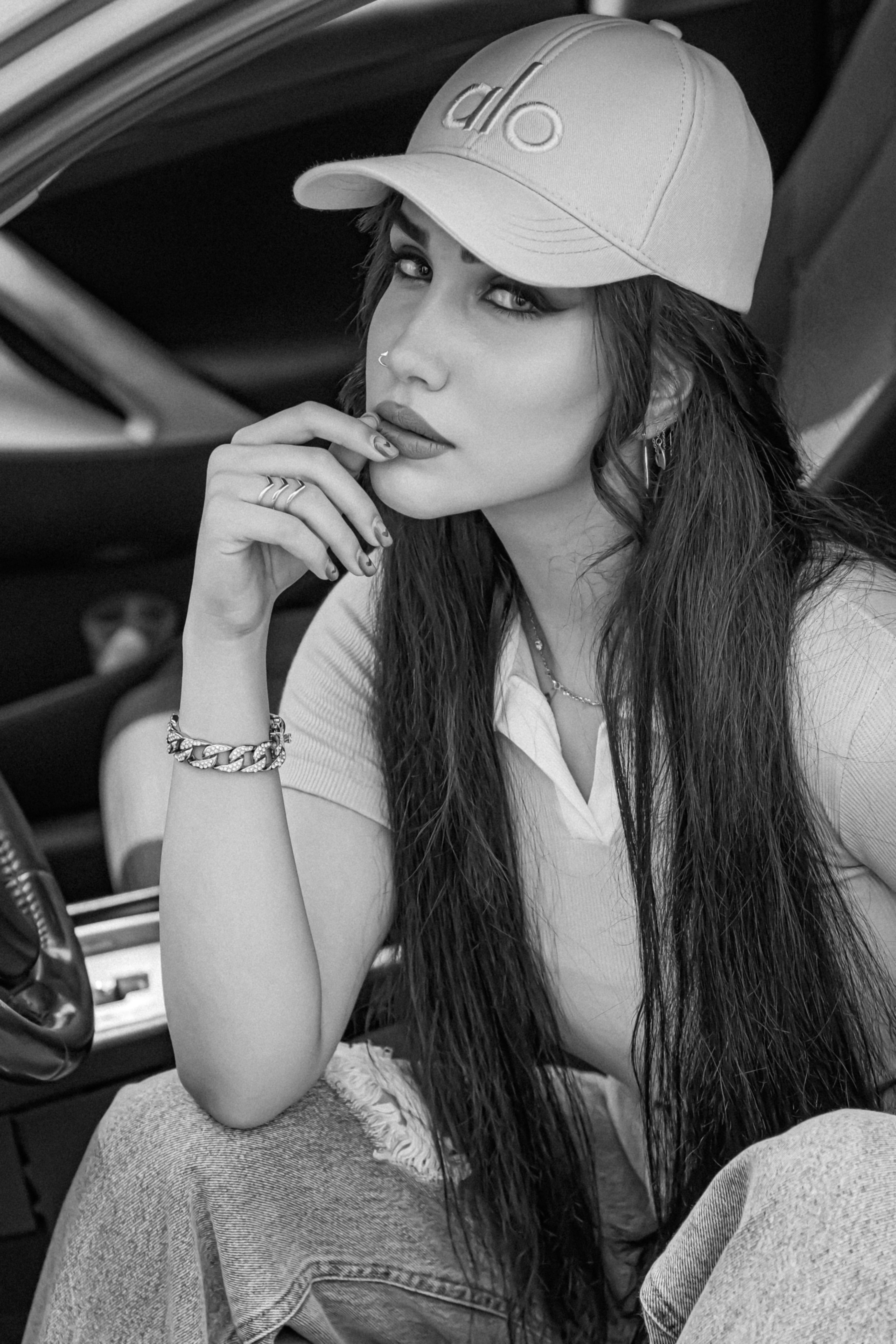 A fashionable woman in a cap sits stylishly inside a car. Black and white portrait.