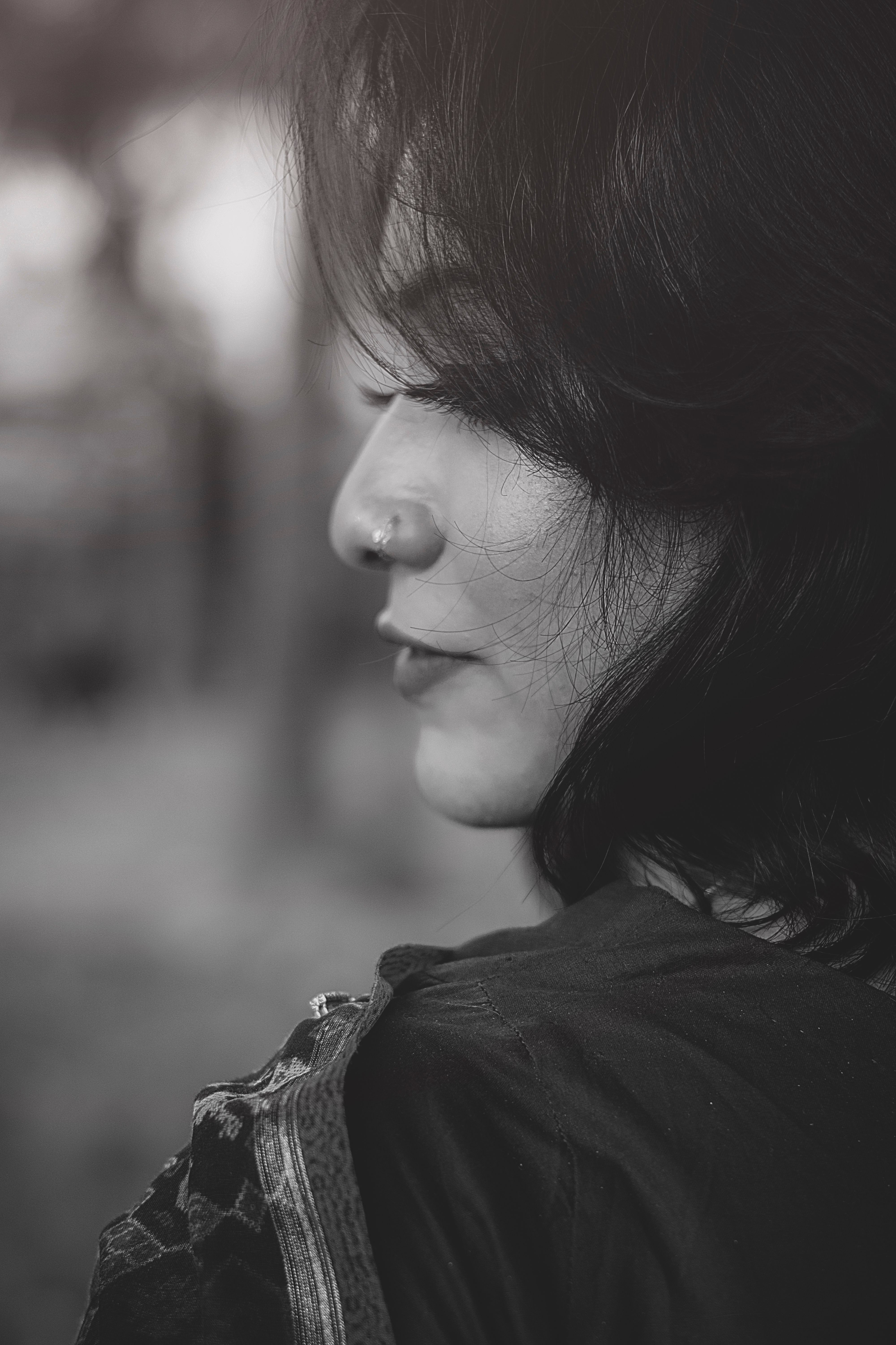 Artistic black and white side profile of a woman with a serene expression, outdoors.