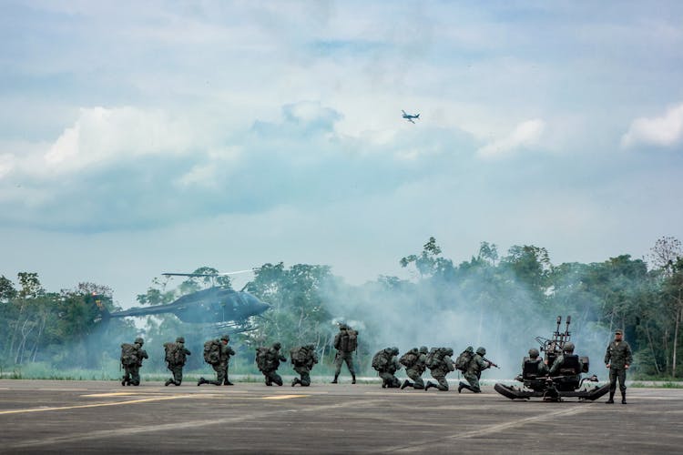 Unrecognizable Soldiers With Infantry Weapons Accomplishing Military Mission Near Helicopter