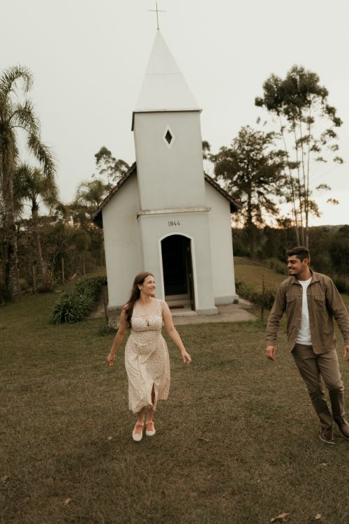 Free A joyful couple walks hand in hand near a charming small chapel. Stock Photo