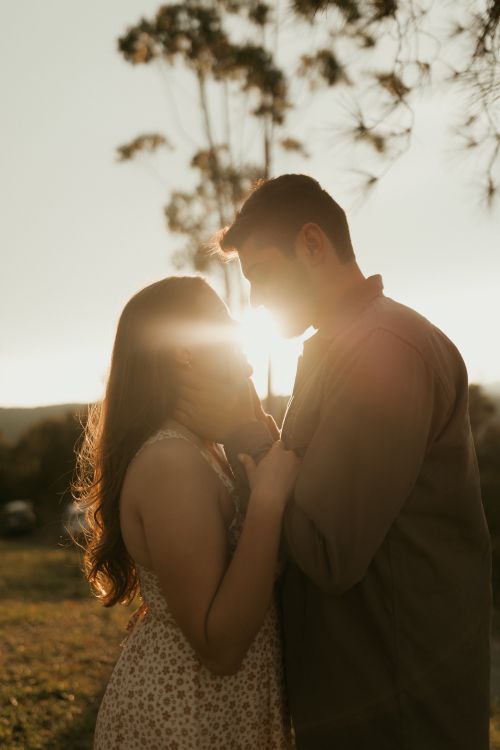 Free A romantic moment with a couple embracing in the warm glow of a sunset outdoors. Stock Photo