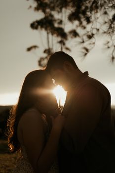 A couple sharing a tender moment in a romantic silhouette against the sunset.