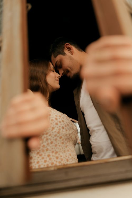 Free A tender moment between a romantic couple leaning towards each other inside a warm setting. Stock Photo
