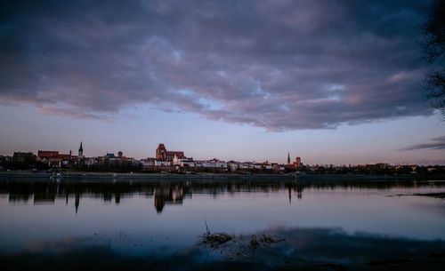 Free Tranquil twilight view of Toruń's skyline reflected in the Vistula River. Stock Photo