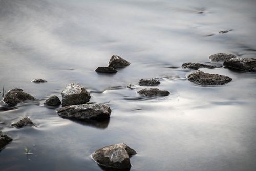 Free Serene rocky stream with smooth water surface, creating a calming atmosphere. Stock Photo
