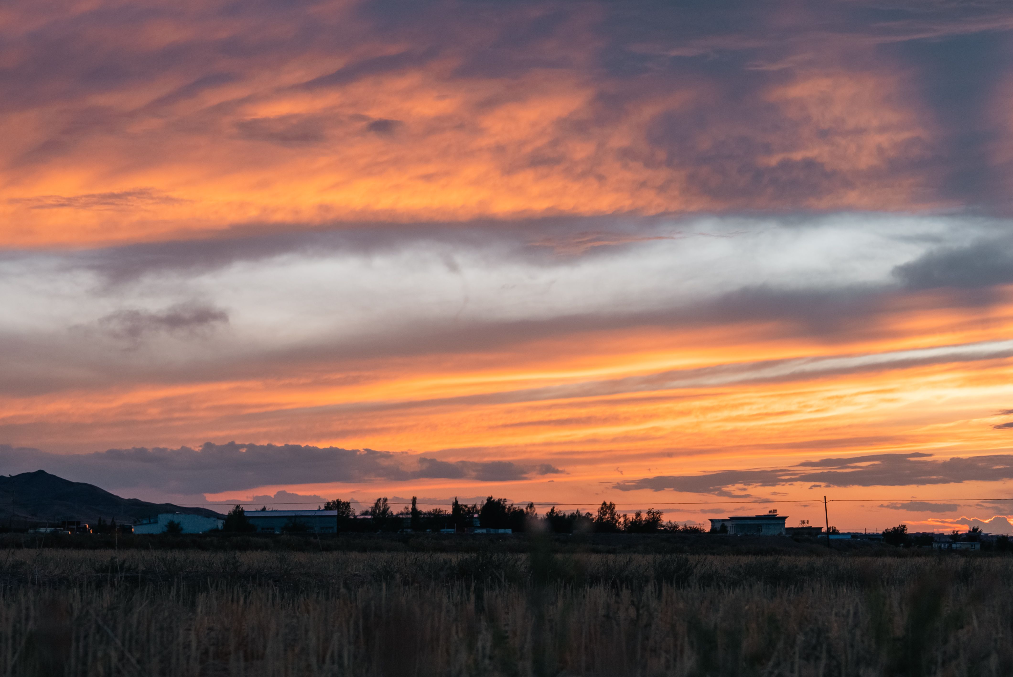 Vibrant sunset sky over a quiet rural landscape, showcasing brilliant colors.