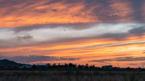 Vibrant sunset sky over a quiet rural landscape, showcasing brilliant colors.