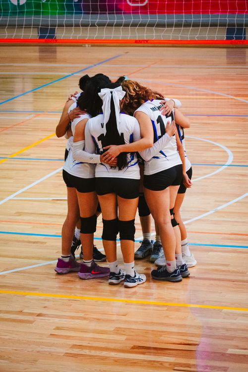 Free A women's volleyball team huddles on an indoor court in Mexico City, showcasing team spirit and unity. Stock Photo