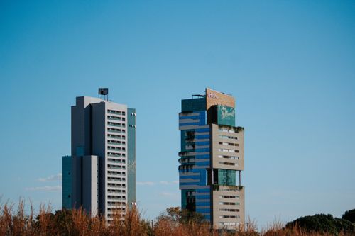Free Two modern skyscrapers contrasting against a clear blue sky, highlighting urban architecture. Stock Photo