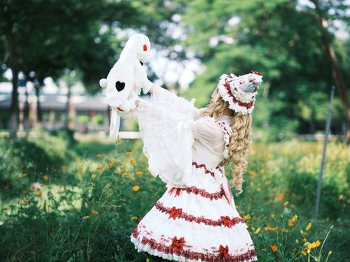 Free A young woman in a Lolita dress lifts a stuffed toy outdoors. Stock Photo