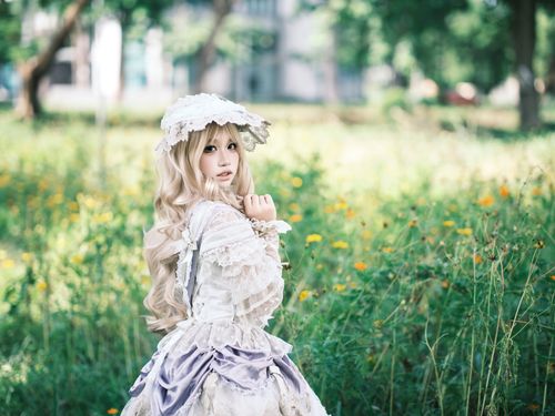 Free A woman in Victorian-style cosplay dress poses outdoors in a lush green meadow. Stock Photo