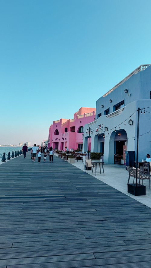 Free Colorful waterfront with people strolling along vibrant buildings in Dubai. Stock Photo