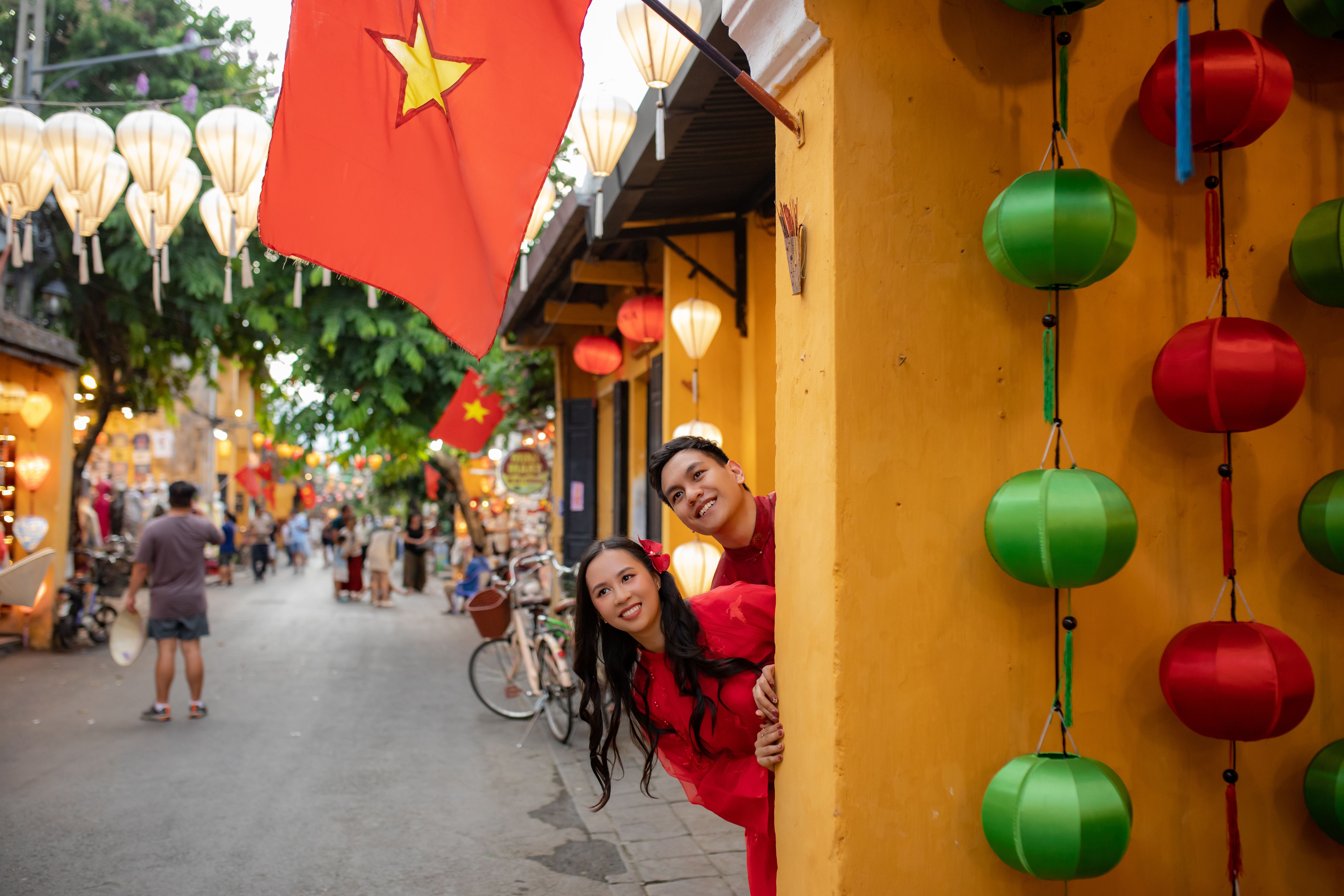 Smiling couple enjoying colorful lanterns on a vibrant street in Đà Nẵng, Vietnam.