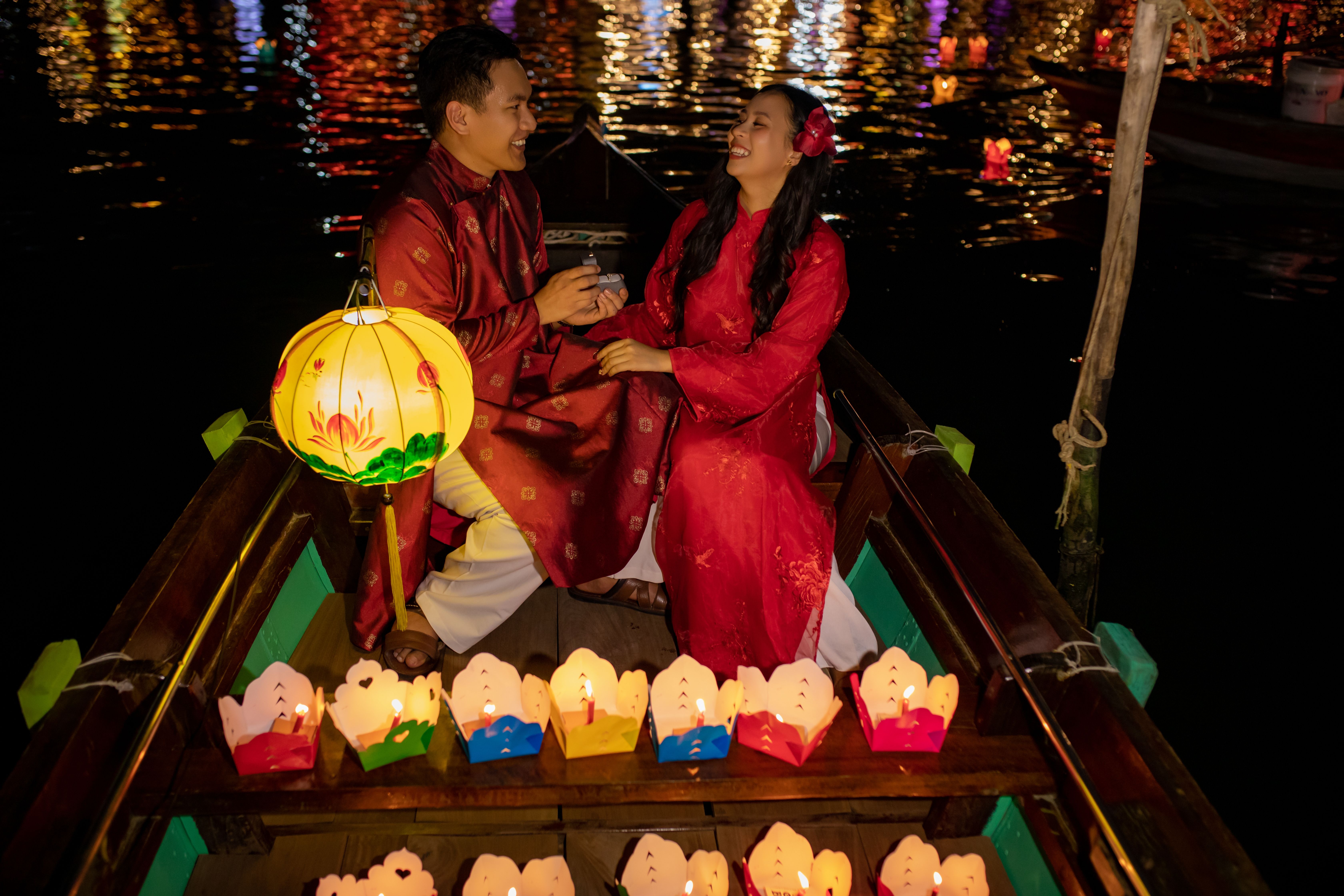 Couple enjoying a romantic lantern boat ride in Đà Nẵng at night, surrounded by colorful lights.
