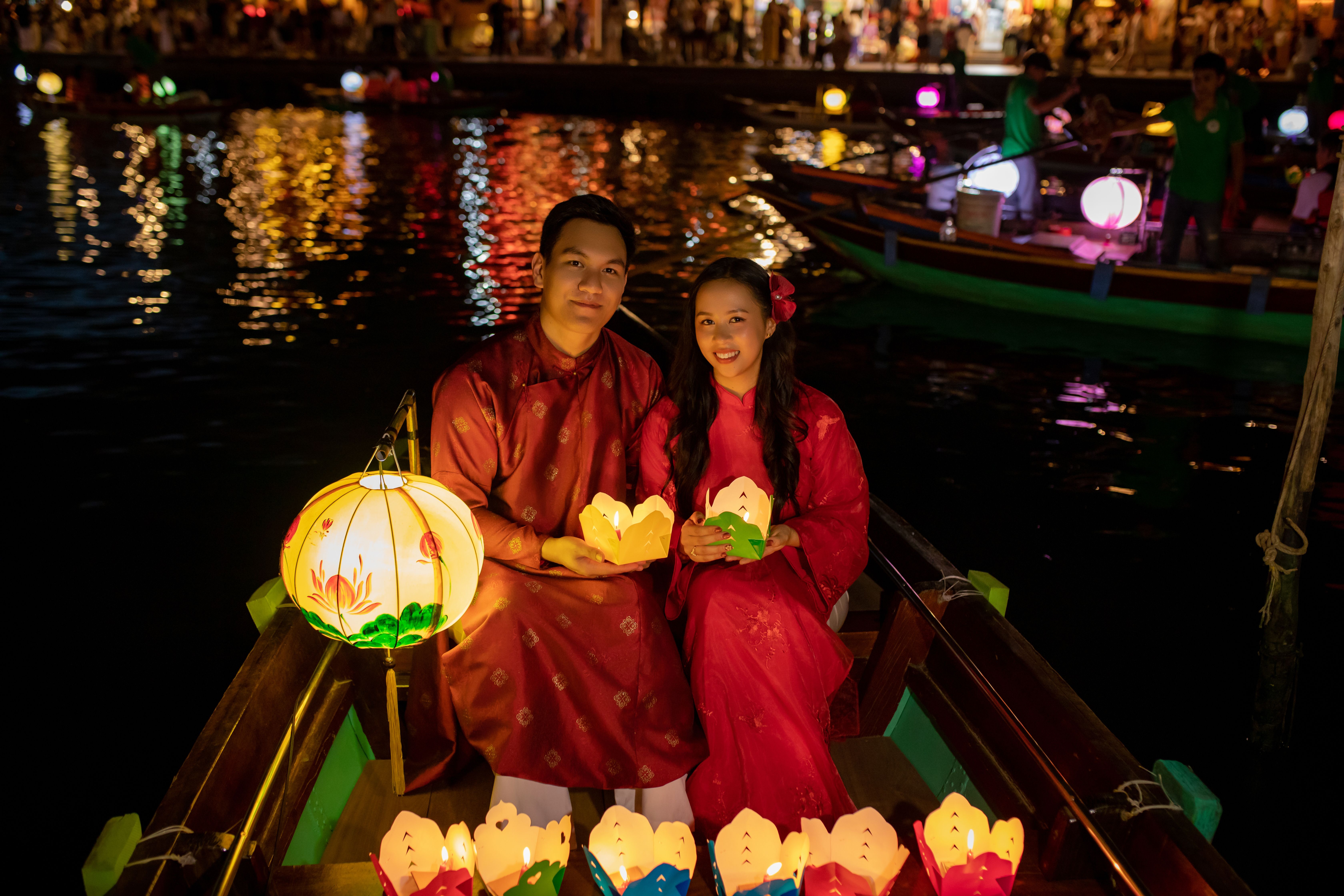 Couple celebrating Lantern Festival in Đà Nẵng, Việt Nam, with traditional attire and floating lanterns.