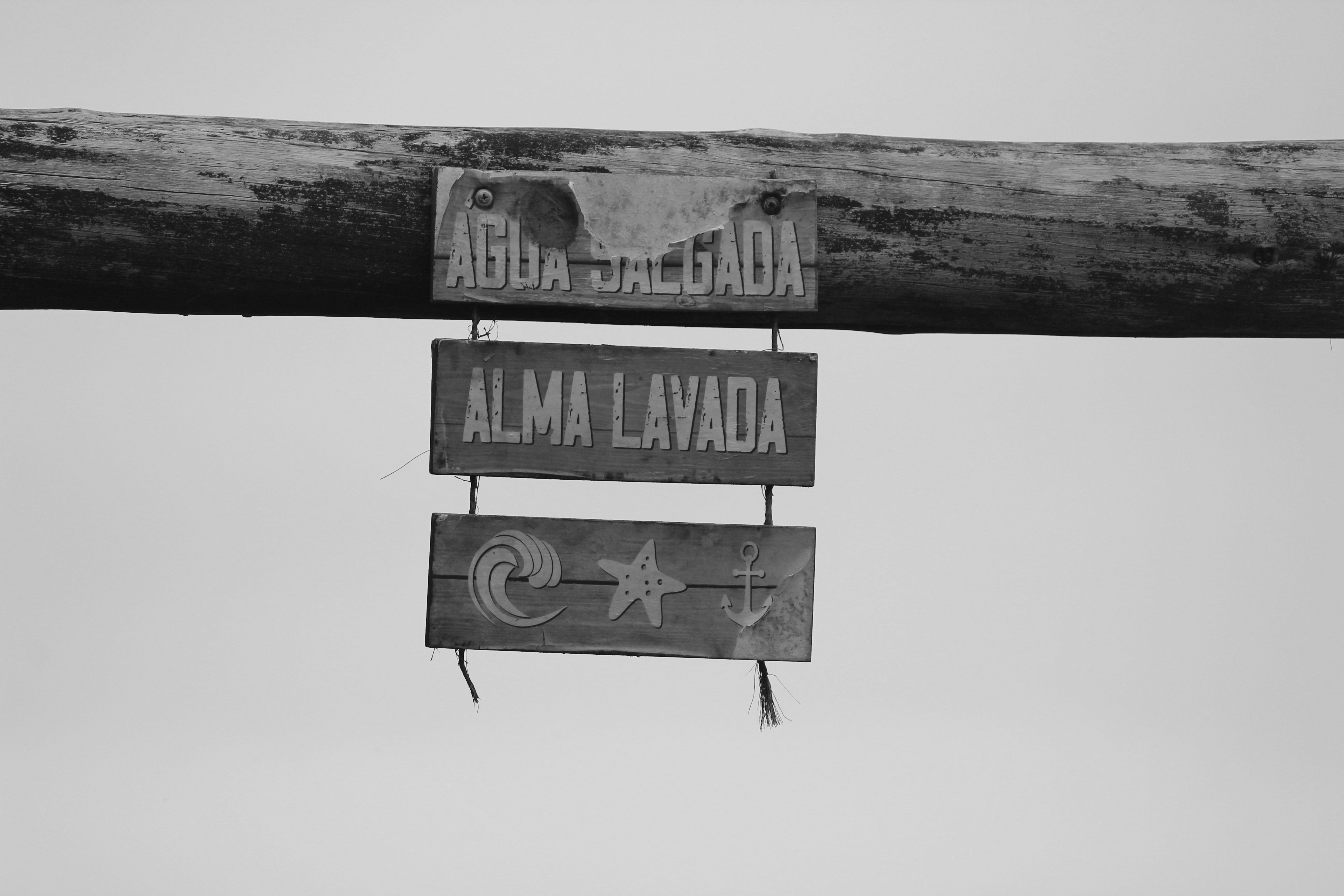 Black and white photo of a rustic beach sign in Guaratuba, Paraná, Brazil.