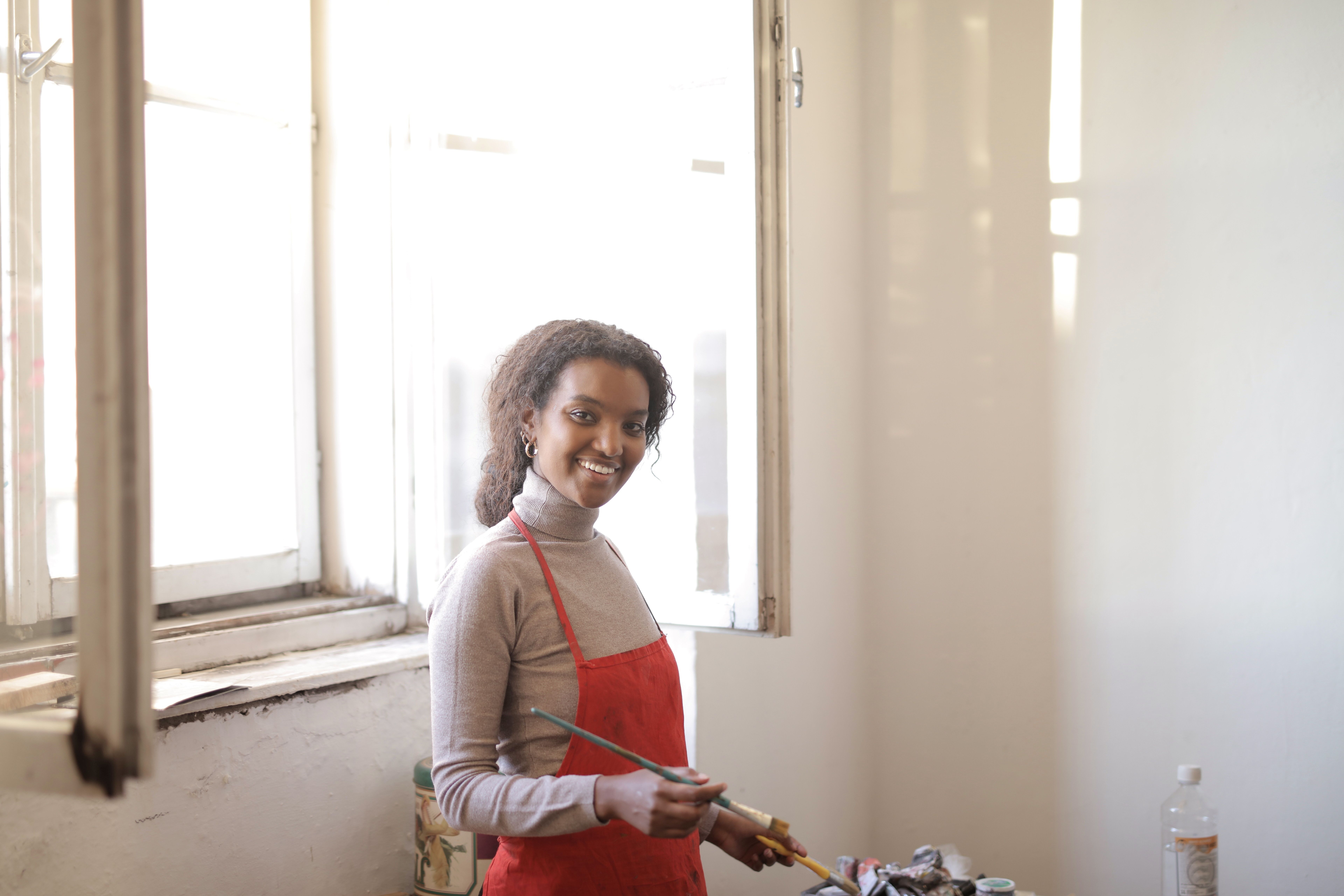 Cheerful black female with paintbrush in studio · Free Stock Photo