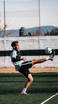 Dynamic action shot of a young soccer player executing a powerful kick during a practice session on an outdoor field.