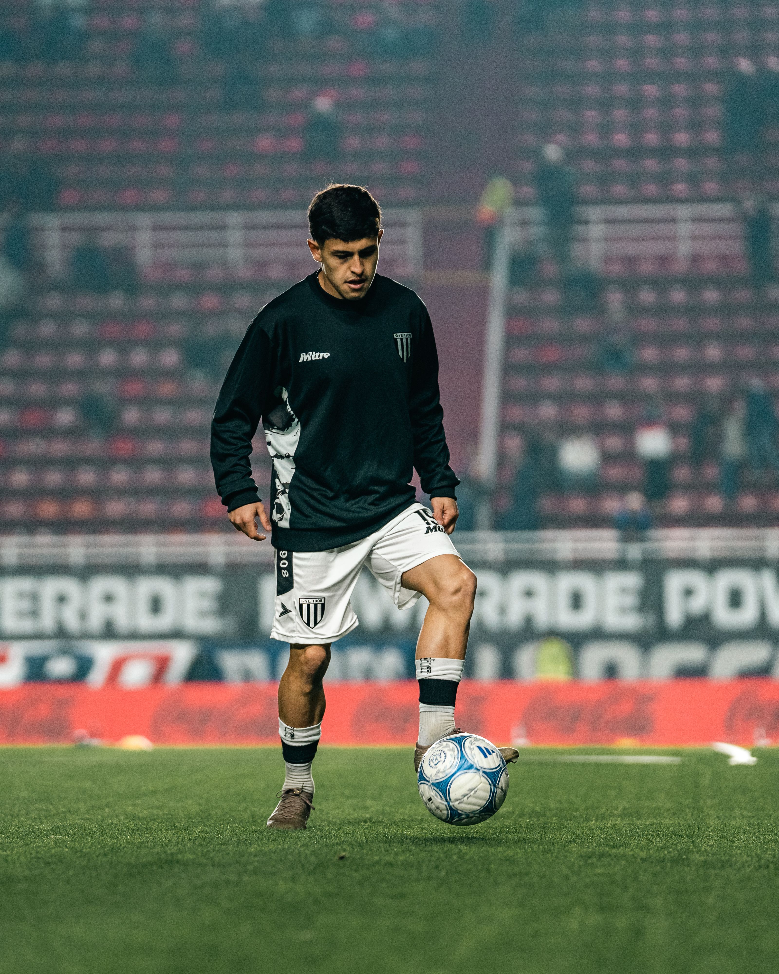 Football player training on a field inside a stadium
