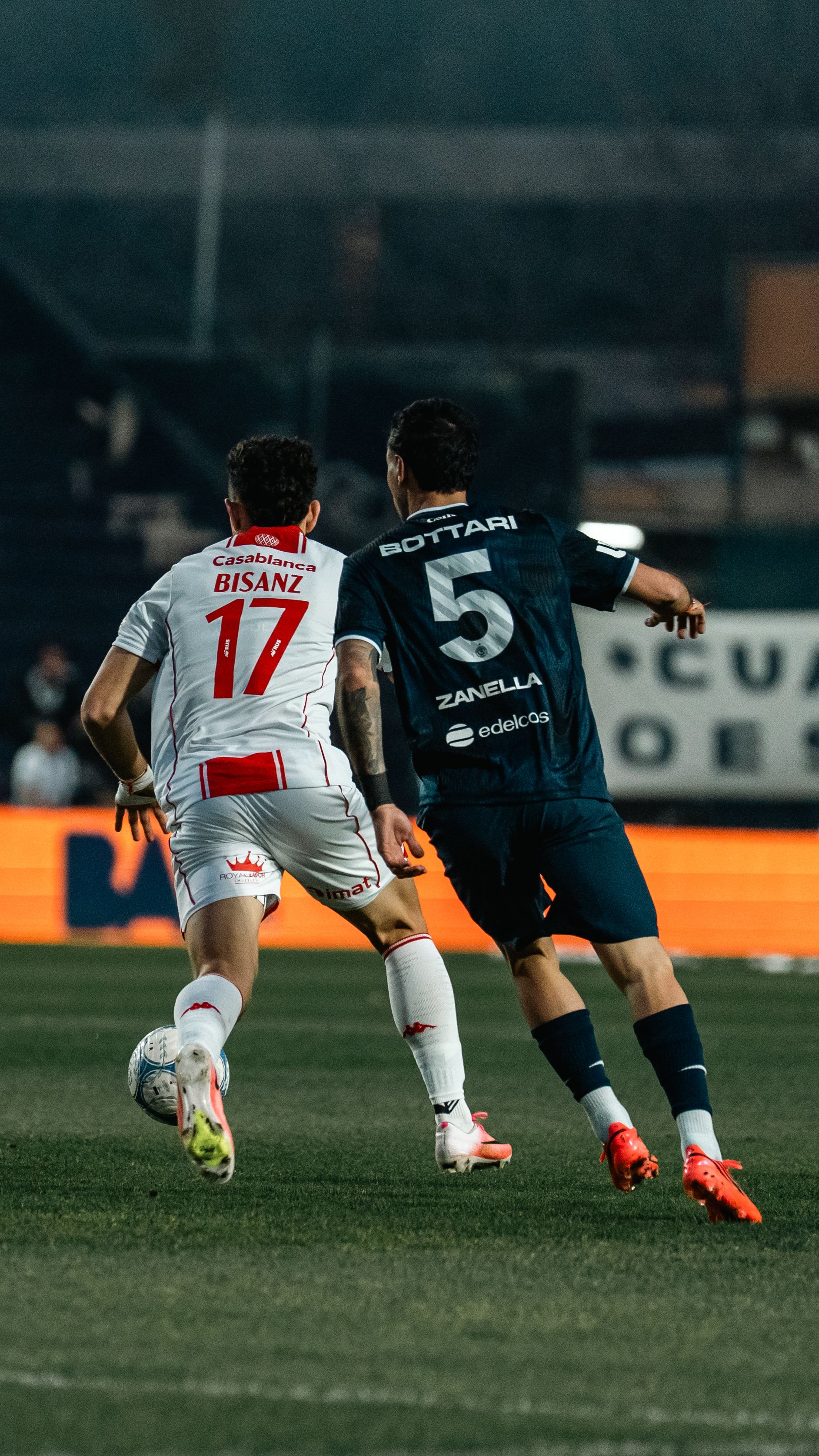 Two soccer players in action during a night match, showcasing athleticism and competition.
