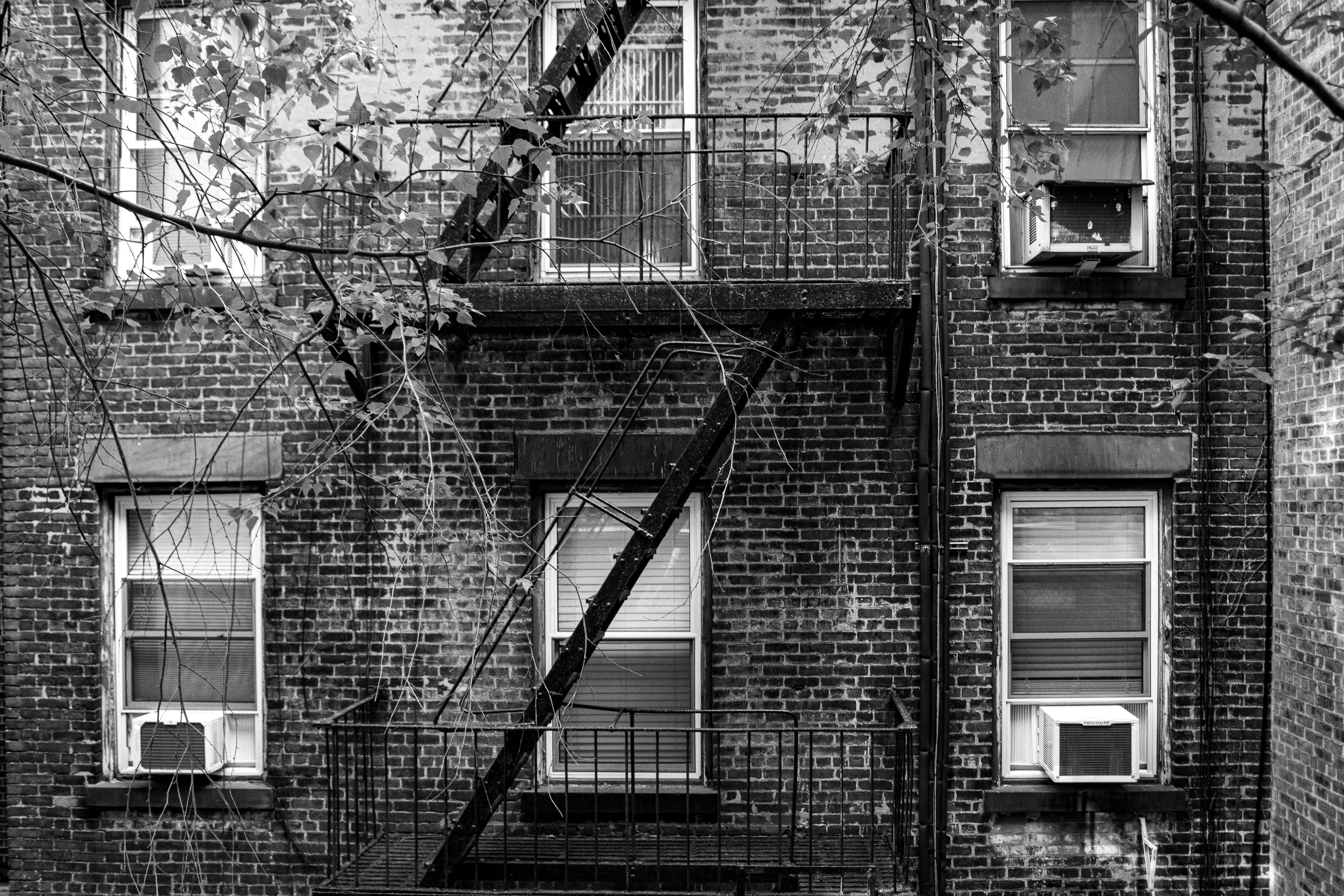 Grunge facade of New York building with fire escape in monochrome.