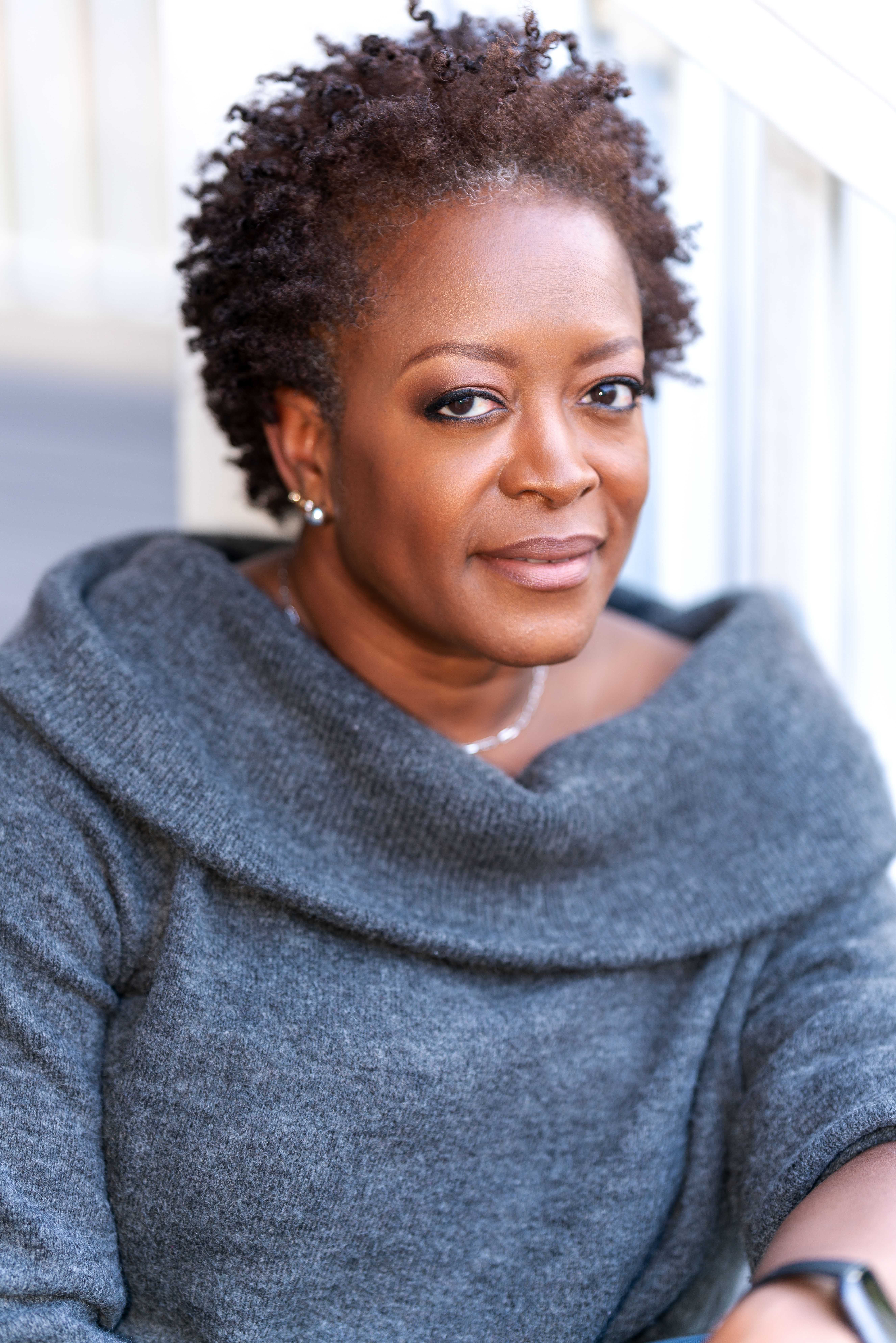 Stunning portrait of an adult woman with a confident and introspective expression in a cozy gray sweater.