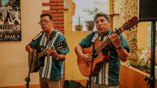 Free Two Mexican musicians performing with acoustic guitars indoors. Stock Photo
