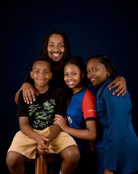 A joyful family portrait featuring four people smiling in a studio setting.