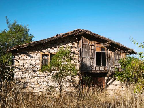 Free A rustic abandoned stone house with wooden accents, surrounded by nature. Stock Photo