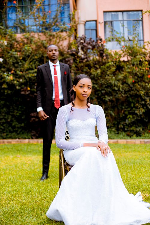 Free A couple dressed in formal attire posing in a garden setting, exuding elegance and warmth. Stock Photo