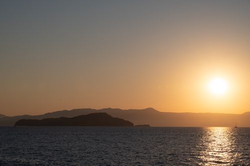 Free Serene sunset over the sea near Chania, Greece, with calm water and distant islands. Stock Photo
