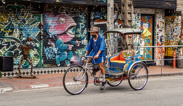 A vibrant street scene featuring a bicycle rickshaw in front of colorful graffiti art.
