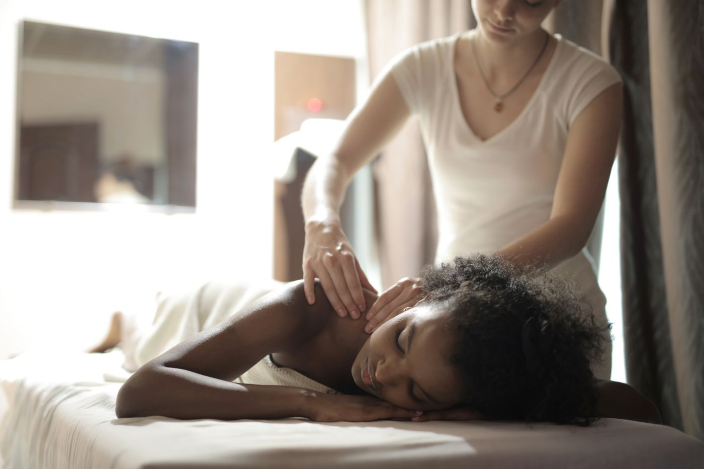 Professional therapist performing a focused shoulder massage on a young Black woman